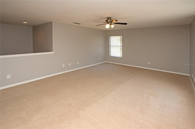 empty room with ceiling fan, light colored carpet, and a textured ceiling