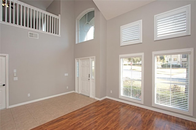 foyer entrance featuring a towering ceiling and wood-type flooring