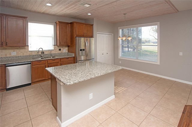 kitchen featuring pendant lighting, sink, appliances with stainless steel finishes, a center island, and light stone counters