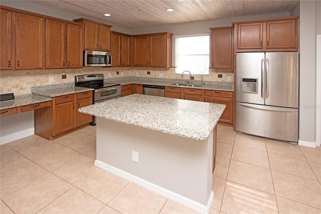 kitchen with light stone countertops, appliances with stainless steel finishes, a center island, and light tile patterned floors