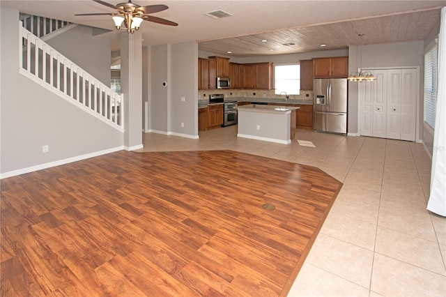 kitchen featuring pendant lighting, sink, light tile patterned floors, stainless steel appliances, and a center island