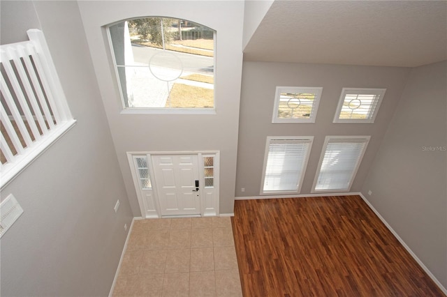 entryway with hardwood / wood-style floors, plenty of natural light, and a high ceiling