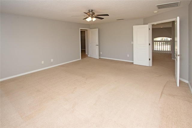 unfurnished bedroom with ceiling fan, light colored carpet, and a textured ceiling