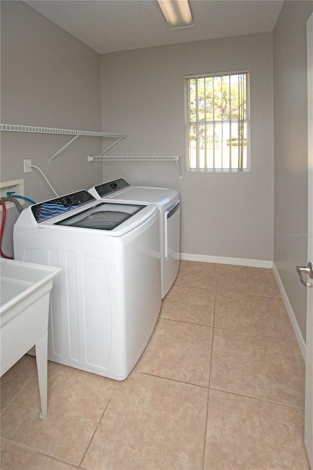 clothes washing area with separate washer and dryer, light tile patterned floors, and sink