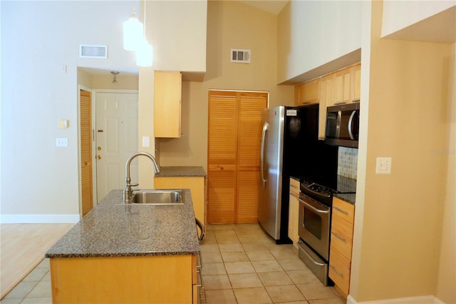 kitchen featuring sink, appliances with stainless steel finishes, hanging light fixtures, a high ceiling, and light tile patterned flooring