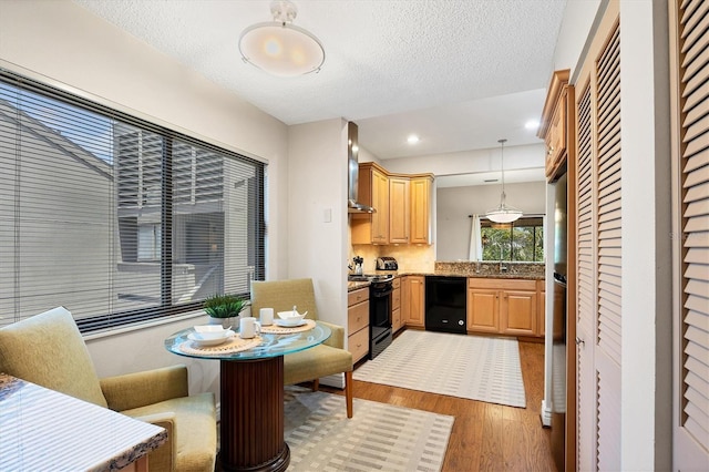 kitchen featuring black appliances, pendant lighting, wall chimney exhaust hood, hardwood / wood-style flooring, and a textured ceiling