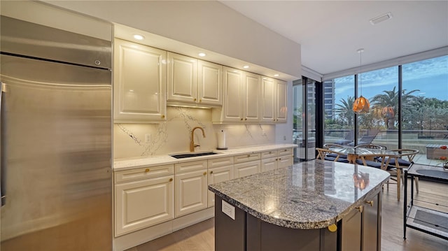 kitchen featuring a center island, stainless steel built in refrigerator, sink, backsplash, and floor to ceiling windows