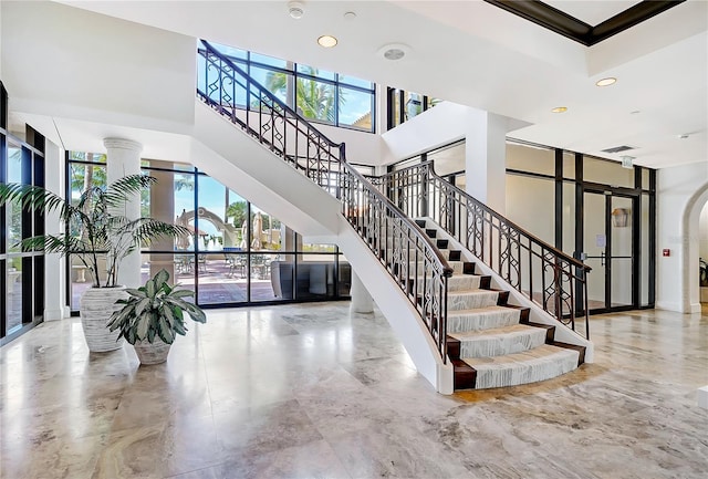 staircase featuring a towering ceiling and french doors