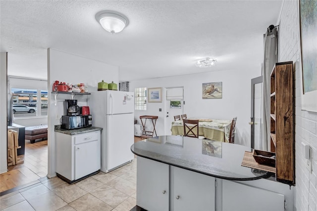 kitchen featuring a textured ceiling, white fridge, and light tile floors