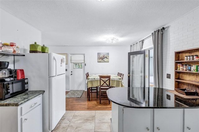 kitchen featuring dark stone countertops, kitchen peninsula, a textured ceiling, and light tile floors