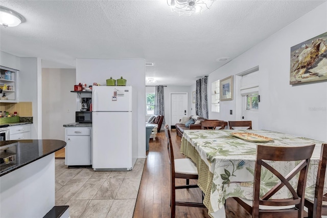 kitchen featuring white fridge, light hardwood / wood-style floors, and a textured ceiling