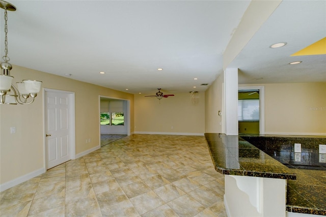 interior space with ceiling fan with notable chandelier and hanging light fixtures