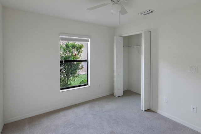 unfurnished bedroom with light carpet, a closet, multiple windows, and ceiling fan