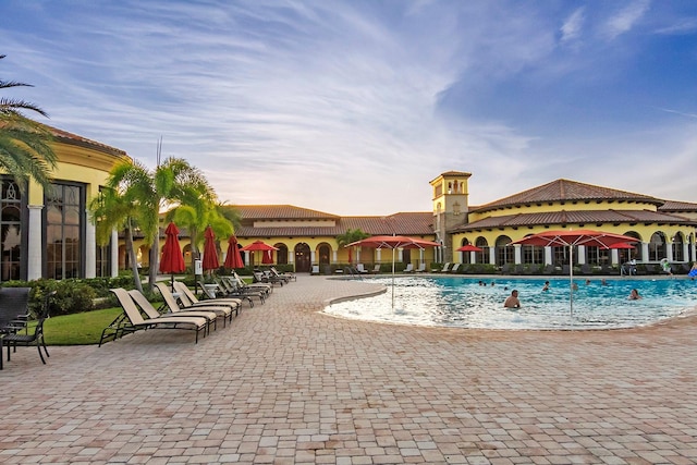 pool at dusk with a patio area