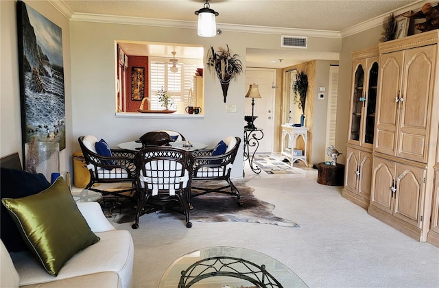 dining space with a textured ceiling, light colored carpet, and crown molding