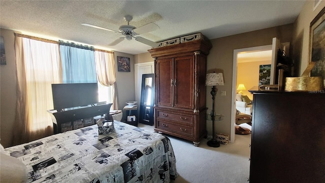 carpeted bedroom featuring ceiling fan and a textured ceiling