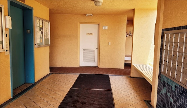 interior space with a mail area, light tile patterned floors, a textured ceiling, and elevator