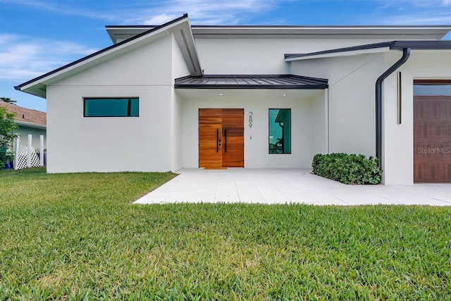 back of property with a garage and a lawn