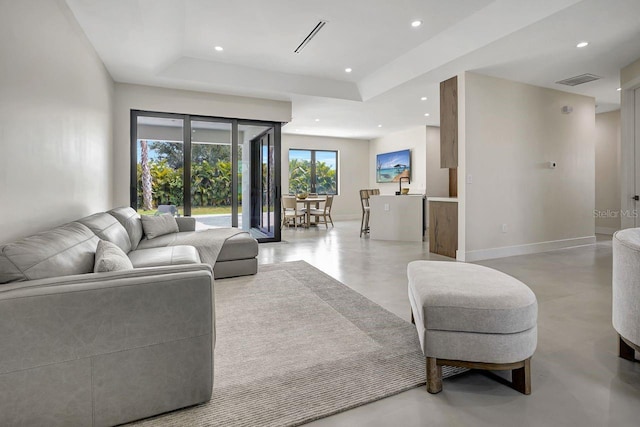 living room with concrete floors and a tray ceiling