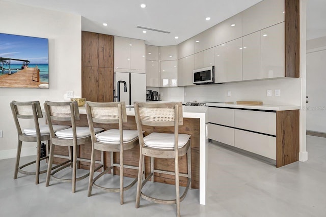 kitchen with a kitchen breakfast bar, white cabinets, and built in fridge