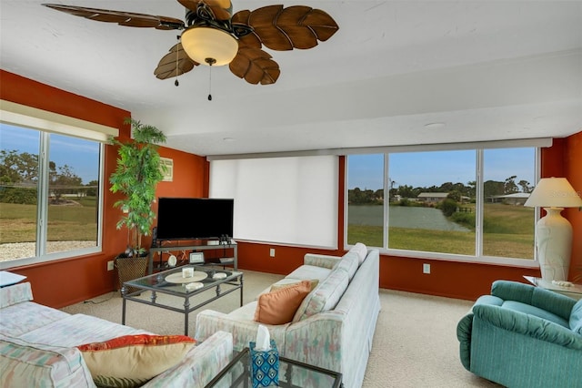 living room with a water view, ceiling fan, and carpet floors