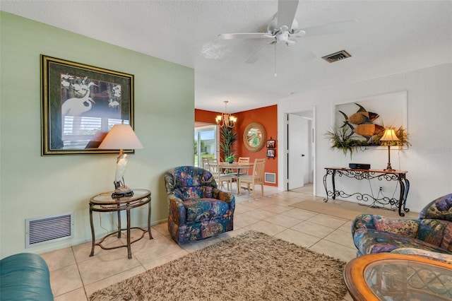 tiled living room with a textured ceiling and ceiling fan with notable chandelier