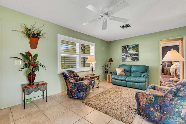 living room with tile flooring, ceiling fan, and a textured ceiling