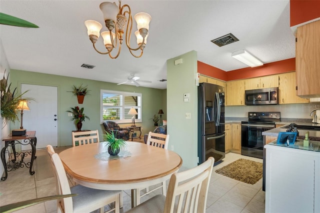 tiled dining room featuring sink and ceiling fan with notable chandelier