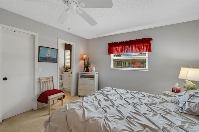 carpeted bedroom featuring ensuite bathroom, ceiling fan, and a textured ceiling