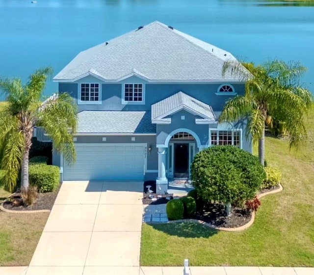 view of front of property with a garage, a front lawn, and a water view