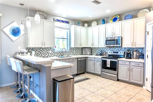 kitchen with hanging light fixtures, tasteful backsplash, kitchen peninsula, and stainless steel appliances