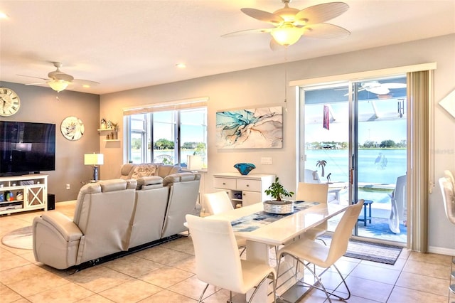 dining space featuring a water view, ceiling fan, and light tile flooring