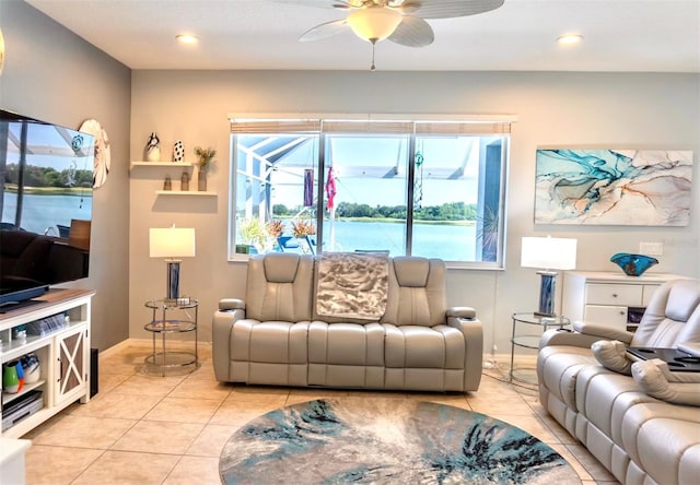 tiled living room with ceiling fan and a water view