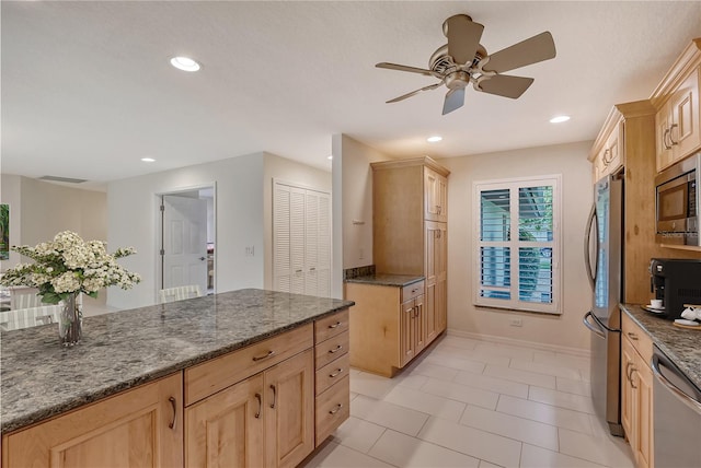 kitchen featuring light brown cabinets, dark stone counters, ceiling fan, appliances with stainless steel finishes, and light tile floors