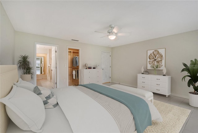 bedroom with ceiling fan, a closet, a walk in closet, and light tile floors