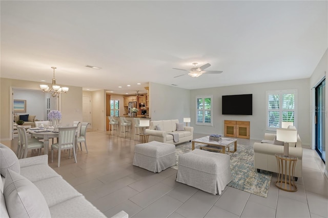 living room featuring ceiling fan with notable chandelier and light tile floors