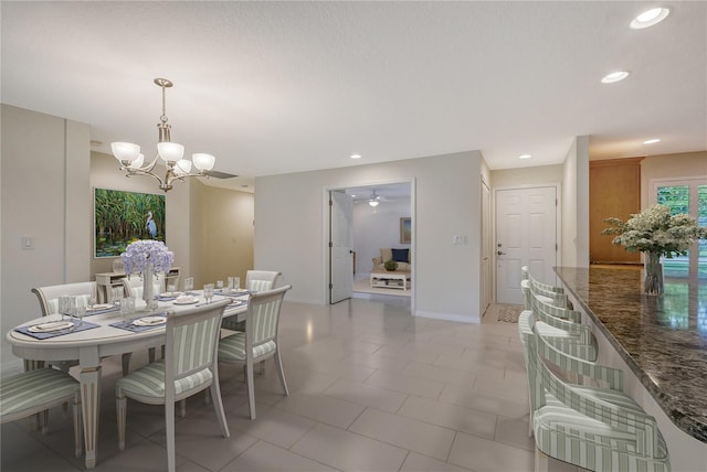 dining area featuring tile floors and ceiling fan with notable chandelier