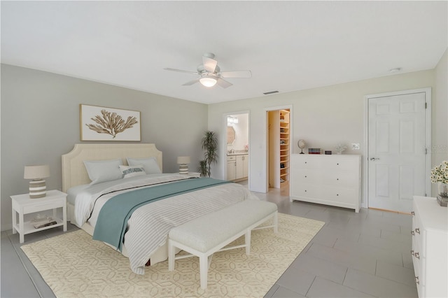 tiled bedroom featuring a walk in closet, a closet, ceiling fan, and connected bathroom