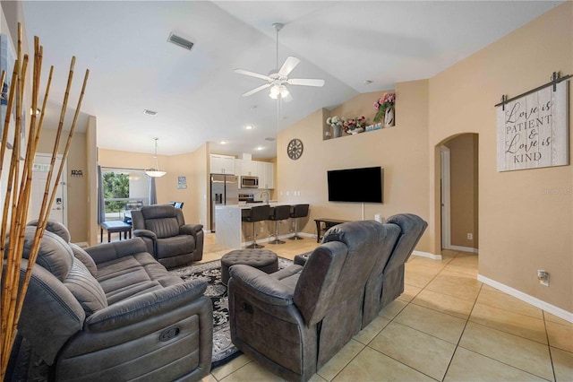 living room featuring ceiling fan, light tile floors, and lofted ceiling