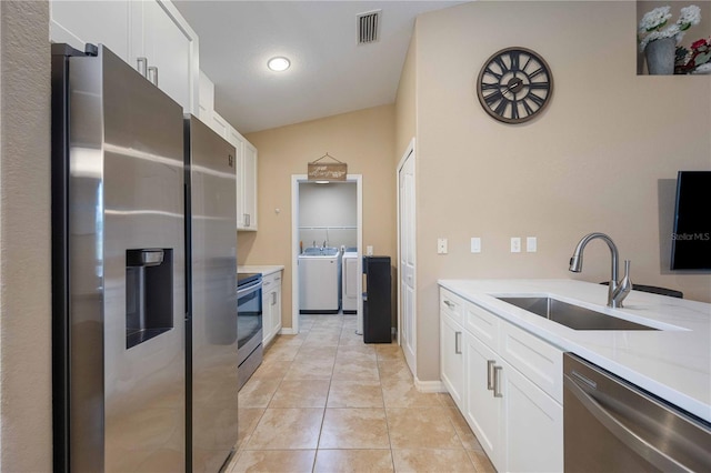 kitchen featuring vaulted ceiling, light tile flooring, sink, white cabinetry, and appliances with stainless steel finishes