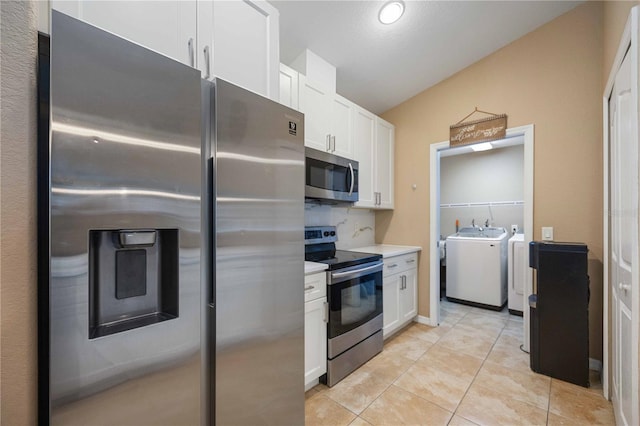 kitchen featuring stainless steel appliances, washer and clothes dryer, white cabinetry, and light tile floors