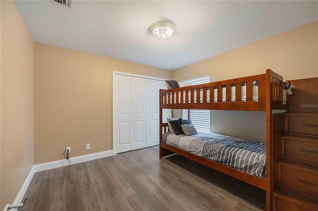 bedroom with a closet, a textured ceiling, and dark wood-type flooring