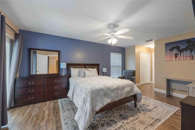 bedroom featuring wood-type flooring, a closet, ceiling fan, and multiple windows