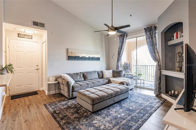 living room featuring high vaulted ceiling, ceiling fan, built in features, and hardwood / wood-style flooring