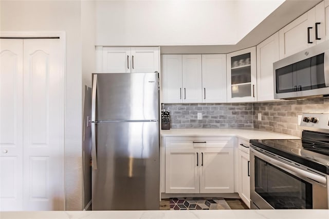 kitchen featuring appliances with stainless steel finishes, white cabinetry, tasteful backsplash, and dark tile floors