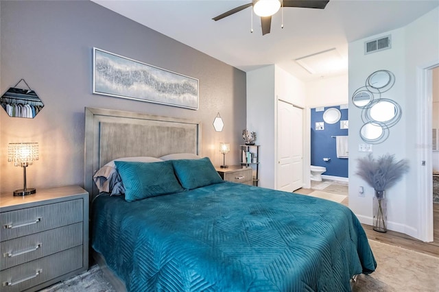 bedroom with light wood-type flooring, ensuite bathroom, and ceiling fan