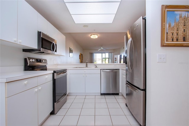 kitchen with light tile patterned floors, stainless steel appliances, sink, and white cabinets