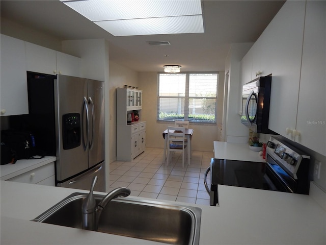 kitchen with light tile patterned floors, appliances with stainless steel finishes, sink, and white cabinets