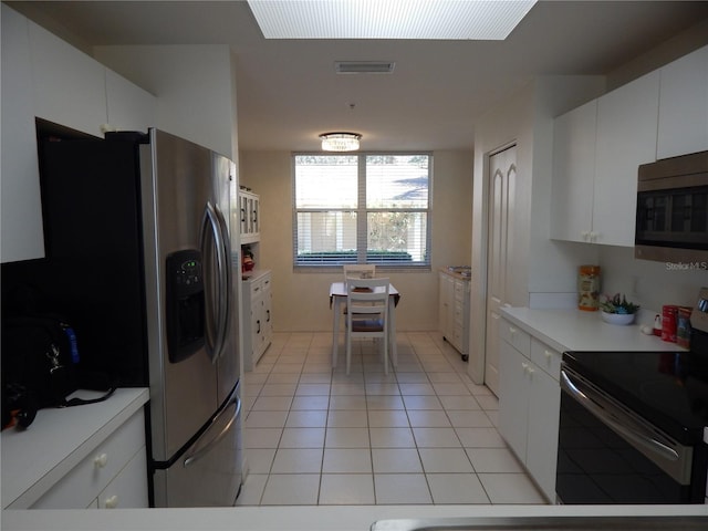 kitchen with stainless steel appliances, light tile patterned floors, and white cabinets