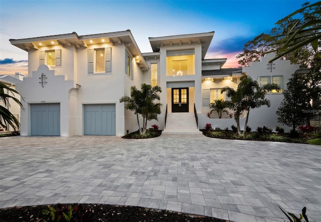 view of front of house featuring stucco siding, a garage, decorative driveway, and french doors